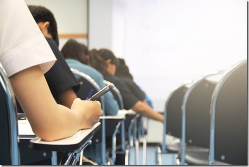 Hands university student holding pen writing /calculator doing examination / study or quiz, test from teacher or in large lecture room, students in uniform attending exam classroom educational school.