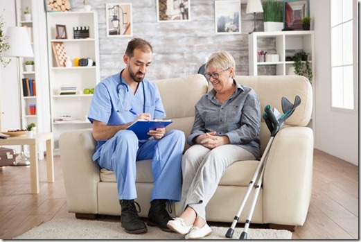 Old woman in nursing home laughing while doctor taking notes on clipboard.