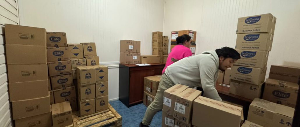 Voluntarios y personal municipal descargando cajas de ayuda humanitaria de un camión de Walmart Chile para familias afectadas por temporales en Valdivia.