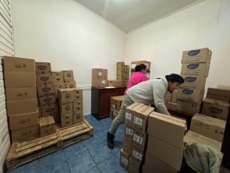 Voluntarios y personal municipal descargando cajas de ayuda humanitaria de un camión de Walmart Chile para familias afectadas por temporales en Valdivia.