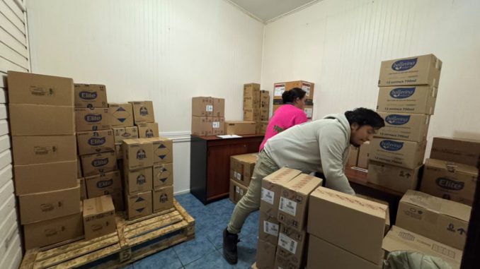 Voluntarios y personal municipal descargando cajas de ayuda humanitaria de un camión de Walmart Chile para familias afectadas por temporales en Valdivia.