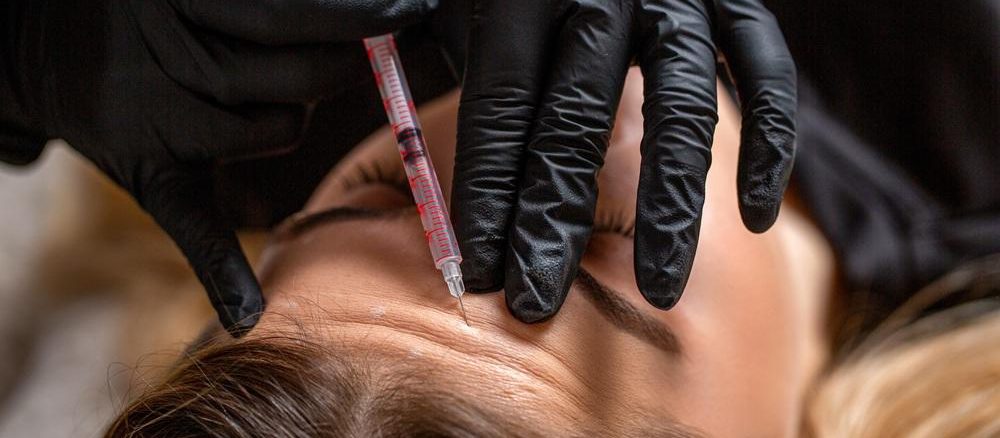 Médico especialista aplicando tratamiento con toxina botulínica en entorno clínico