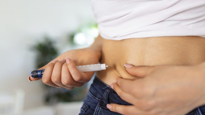 Persona midiendo su cintura con una cinta métrica simbolizando el efecto de medicamentos GLP-1