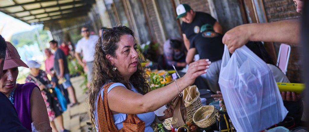 Productores y emprendedores participando en el evento AgroImpacta en el Mercado Estación de Valdivia
