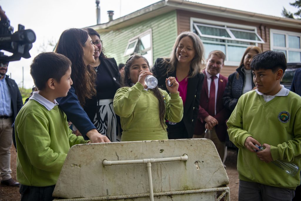 Estudiantes y directora de la Escuela Rural Huillinco posan junto al nuevo sistema de potabilización de agua